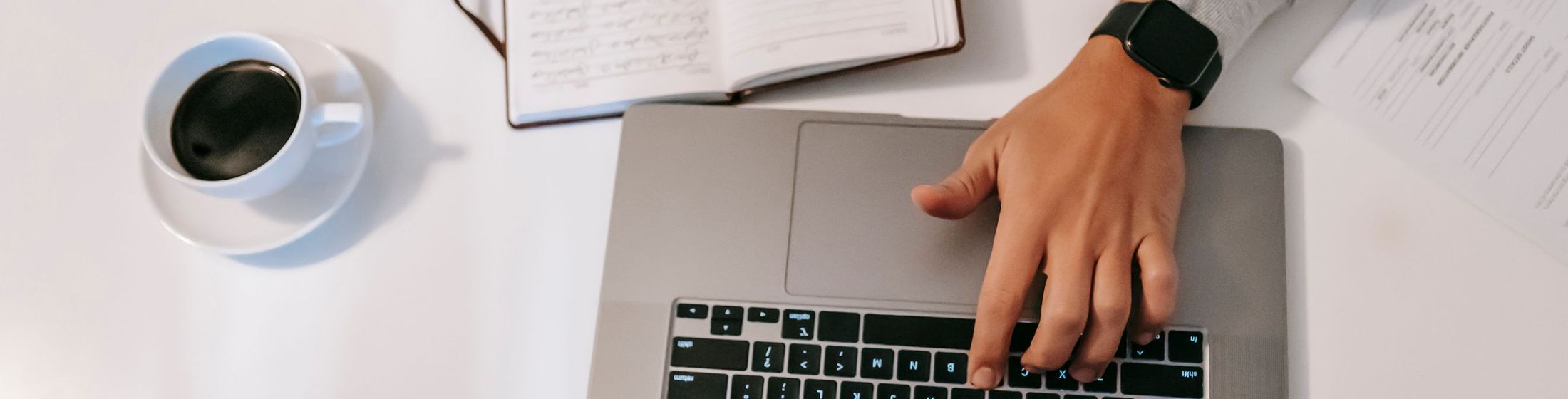 A laptop, notebook and coffee on a desk