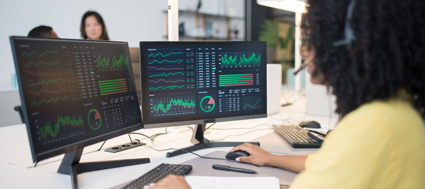 A learner analysing live data dashboards across two screens